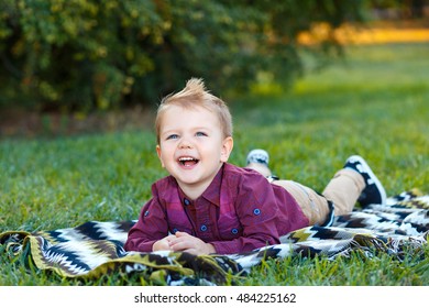 Children Genuine Emotions. Happy Baby Lying On Green Grass And Smiling