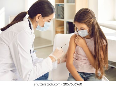 Children getting shots at modern clinic. Young nurse giving injection in the arm to kid in facemask. Doctor gives new effective flu or Covid 19 vaccine to teenage girl who's wearing mouth covering