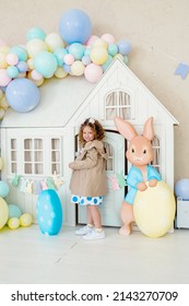 Children Girl In Bunny Ears Dye Colorful Egg For Easter Hunt. Home Decoration With Flowers, Basket And Rabbit For Spring Holiday Celebration.