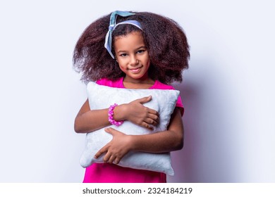 Children girl holding a pillow on a white background. Smiling multiracial kid girl holding cushion. Smile little african american girl hold kissen. Morning little girl - pillow, cushion, kissen. - Shutterstock ID 2324184219