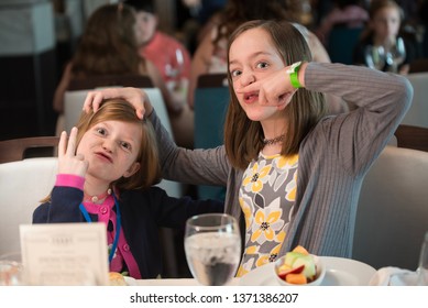 Children Girls Being Crazy And Silly Playing Around At Dinner In Fancy Restaurant.