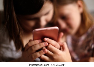 Children Girls With A Smartphone, Children Scare And Threaten The Phone. Child Safety Concept On The Internet And Phone Security In Children's Hands.