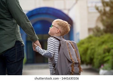 Children Go Back To School. Happy Father And Son Go To Elementary School. Parent Taking Child To Primary School. Pupil Go Study With Backpack. Beginning Of Lessons. First Day Of Fall.