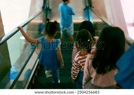 Children are going down using a mall escalator and holding on to the escalator hand rail
