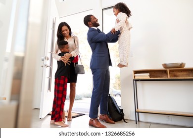 Children Greeting And Hugging Working Parents As They Return Home From Work