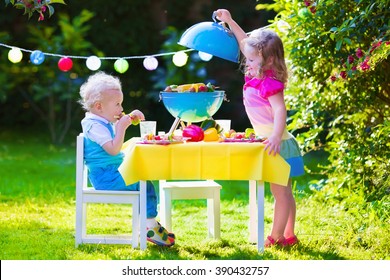 Children grilling meat. Family camping and enjoying BBQ. Brother and sister at barbecue preparing steaks and sausages. Kids eating grill and healthy vegetable meal outdoors. Garden party for child. - Powered by Shutterstock