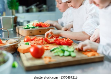Children grind vegetables in the kitchen