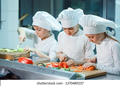 Children grind vegetables in the kitchen