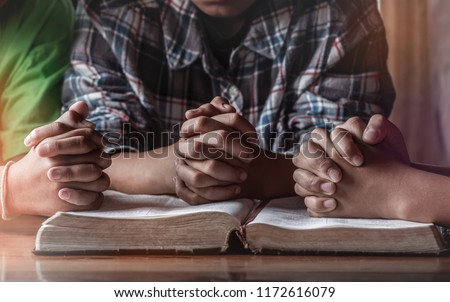 Children group praying on wooden table with open holy bible, prayer meeting concept