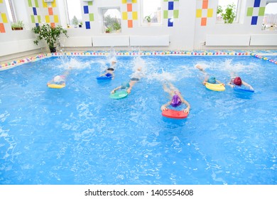 Children Group At Swimming Pool. Shot Of Children's Group Swimming Freestyle At Swimming Lesson. Kindergarten Children In Swimming Lesson. Preschoolers Learn To Swim