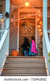 Children In Halloween Costumes  Knocking On Door Of Decorated  Neighborhood  Fun Trick Or Treat Halloween Night. Kids On Halloween Trick Or Treat Happy Holiday. 