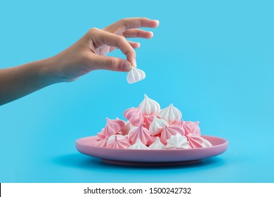 Children hand taking a white meringue from a plate of colourful meringues