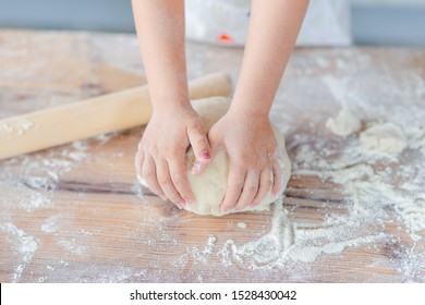 Children hands making the rye dough for backing bread. Kid's hands wheat dough and rolling pin on the table.  Small hands kneading dough. - Powered by Shutterstock