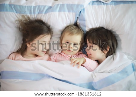 Similar – Image, Stock Photo Happy little girl holding doll and cookie while woman playing with a boy over the bed. Weekend family leisure time concept.