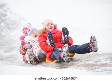 children having fun riding ice slide in winter