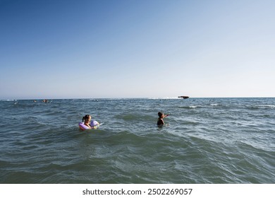 Children having fun in the sea during a summer day at the beach, playing and swimming in the clear blue water in Ulcinj, Montenegro. - Powered by Shutterstock