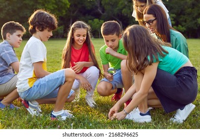 Children having outdoor biology class. Kids learning to take care of nature. Schoolkids, classmates and friends together with teacher sitting on meadow and looking at insects through magnifying glass - Powered by Shutterstock