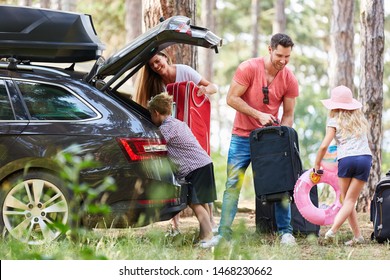 Children help parents carry luggage to the car before traveling on vacation
