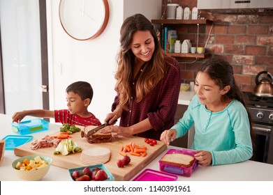Children Helping Mother To Make School Lunches In Kitchen At Home