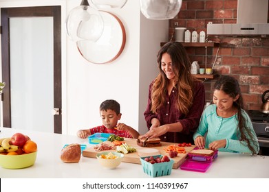 Children Helping Mother To Make School Lunches In Kitchen At Home