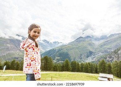Children Hiking In Alps Mountains. Kids Look At Snow Covered Mountain. Spring Family Vacation. Little Girl On Hike Trail In Alpine Meadow. Outdoor Fun And Healthy Activity.