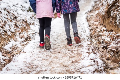 Children hiking in snow mountains forest on family trip. Active family, parents and children trekking in winter in  nature. Kids are walking in the woods trail road in cold snowy winter time.