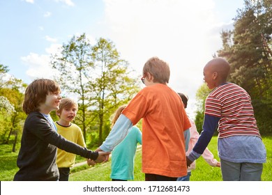 Children hold hands and dance in circles in summer in the park