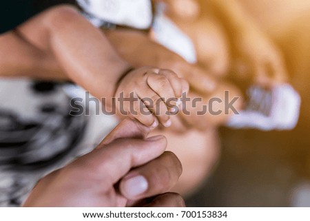 Children are holding father's finger , baby