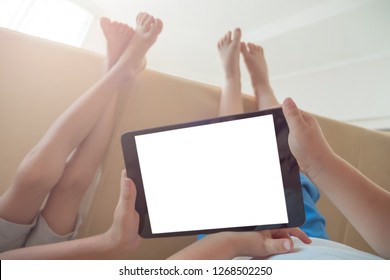 Children holding ipad.  Hands holding tablet with copy space on screen. Barefeet boys lying on the floor. 
Alternative education concept. Copy space. Two boys with tablet.