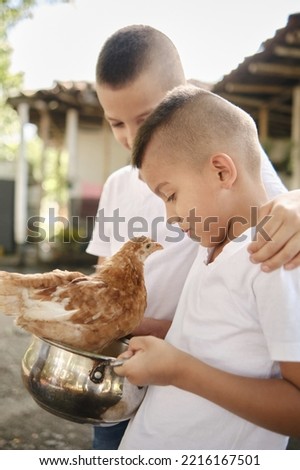 children holding a pot with a chicken in it and looking closely at it