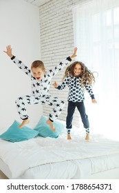 Children Jump On The Bed.The Boy And The Girl Are Having Fun. High Quality Photo. 