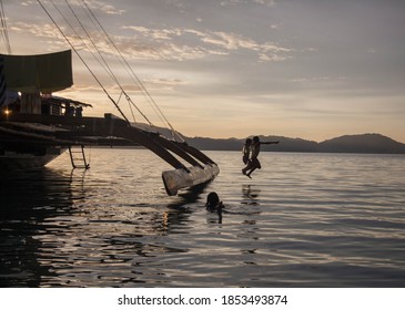 Children Jumping Off From The Traditional Paraw On Sunset