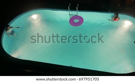 Children kids bathe in the pool at night. Boy and girl teenagers swimming in the pool at night