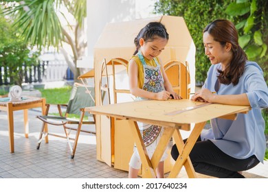 Children Kids Girls And Mother Hand Making  Paper House At Home. Asian Little Child Girl Make And Playing With Cardboard House With Her Mom.