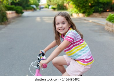 Children learning to drive a bicycle on a driveway outside. Little girls riding bikes on asphalt road in the city. . Active healthy outdoor sports for young children. Fun activity for the baby concept