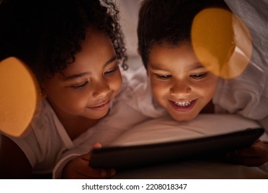 Children Learning On A Digital Tablet While Bonding In Bed At Night, Happy And Relax While Streaming Together. Happy Girl And Boy Awake Late, Enjoying Online Game And Movie While Resting Indoors