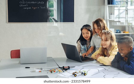 Children learning to program robotic vehicles using a laptop and education software. Group of kids developing computer science skills in a STEM class, doing a coding experiment with robotics. - Powered by Shutterstock