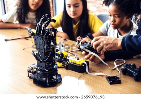 Children learning robotics in a classroom, assembling and programming a robotic hand with guidance. Interactive STEM activity sparks creativity and problem-solving in modern back-to-school education.