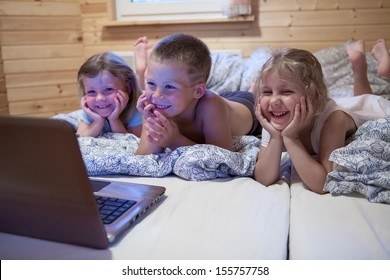 Children looking at laptop with cartoons showing before sleeping in bed