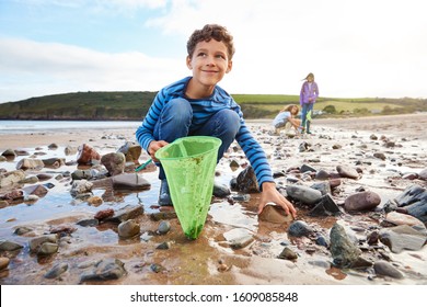 Children Looking In Rockpools On Winter Beach Vacation