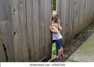children are looking through the hole in the fence