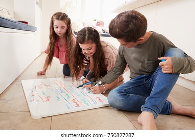 Children Making List Of Chores On Whiteboard At Home