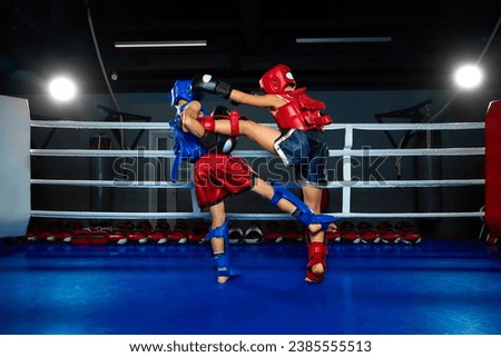 Children, martial fighter exercising kickboxing with sparring partner, fighting in ring at gym. Young professional sportsmen. Concept of sport, healthy lifestyle, hobby, fitness workout, competition.