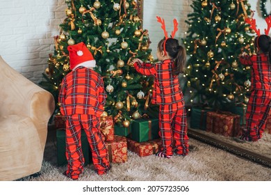 Children In Matching Pajamas Decorate The Christmas Tree.