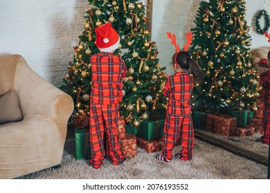 Children In Matching Pajamas Decorate The Christmas Tree.