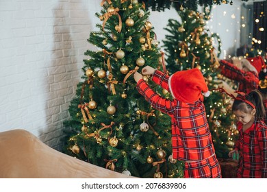 Children In Matching Pajamas Decorate The Christmas Tree.