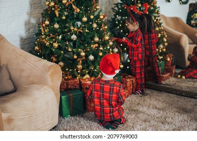 Children In Matching Pajamas Decorate The Christmas Tree.