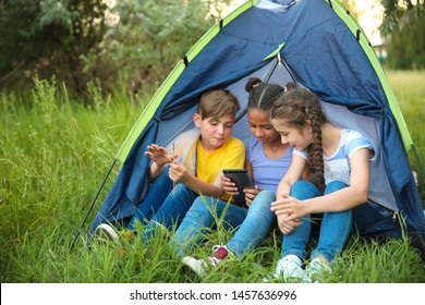 Children with mobile phone sitting near tent at summer camp - Powered by Shutterstock