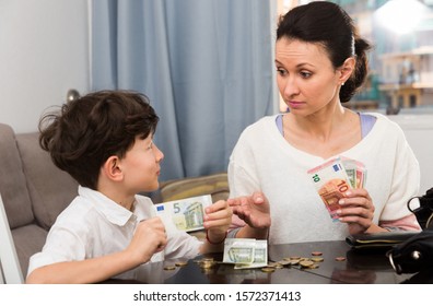 Children And Money Concept. Woman Admonishing Teen Boy While Giving Him Money At Home