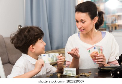 Children And Money Concept. Woman Admonishing Teen Boy While Giving Him Money At Home